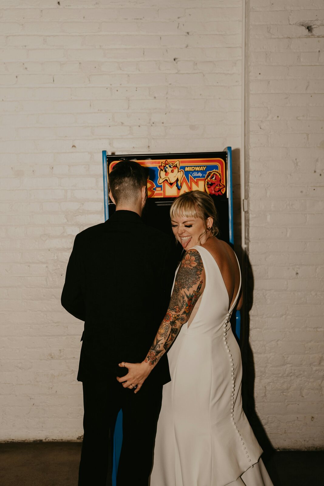Tattooed Colorado bride and groom at a vintage arcade in a quirky wedding portrait