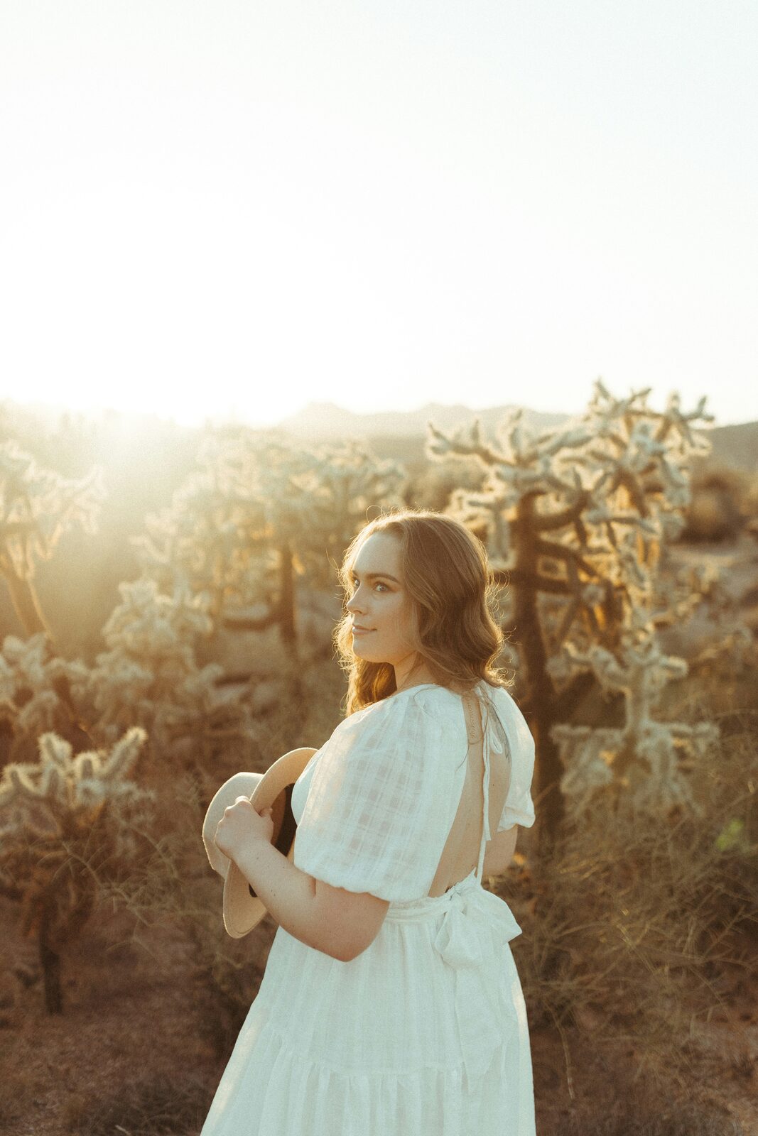 Woman in a white dress among cholla cactus at an Arizona desert sunset, reflecting on marital property in a prenup