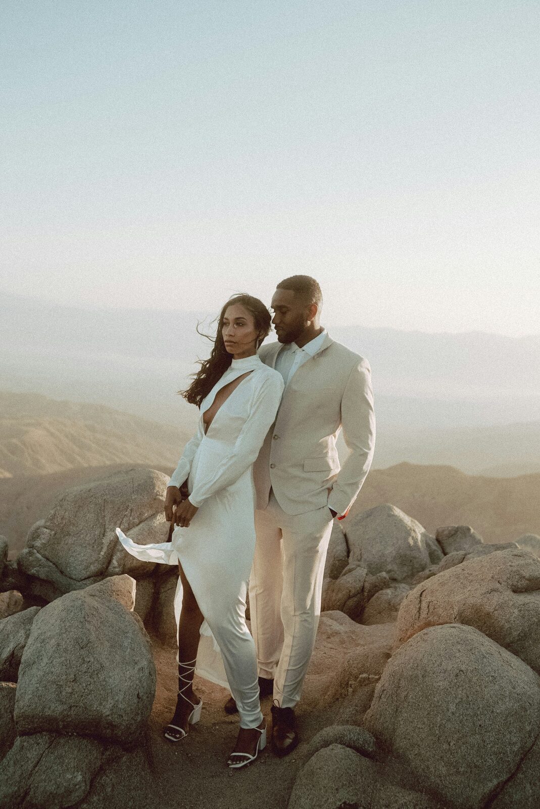 Black bride and groom embracing at golden hour on a rocky summit in an editorial elopement portrait