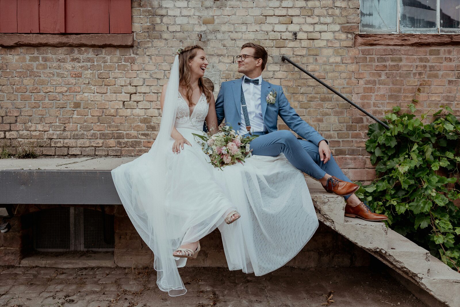 South Carolina bride and groom laughing against a brick wall in fall layers, reflecting the range of assets a prenup can protect