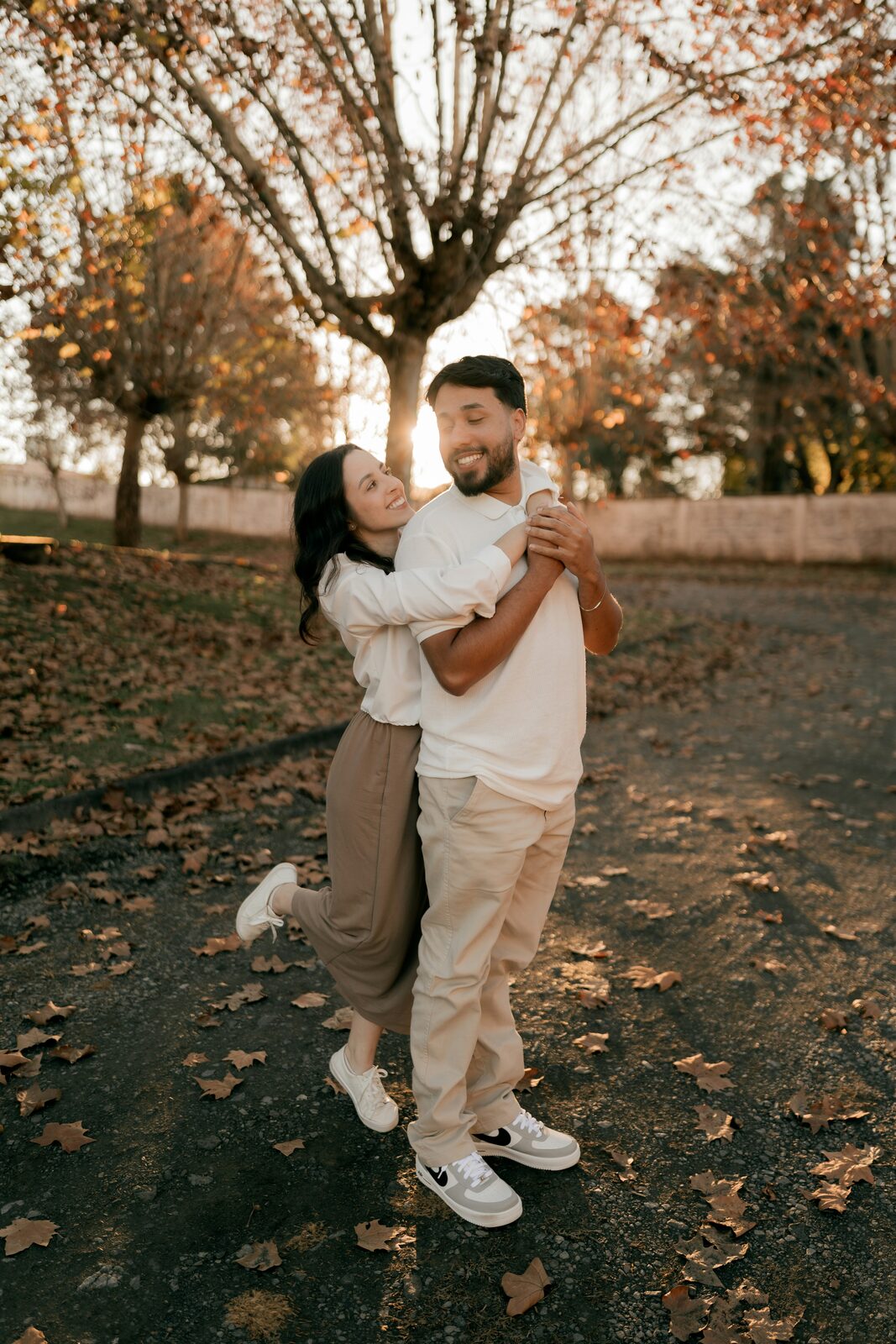 Engaged Minnesota couple hugging among autumn leaves at sunset