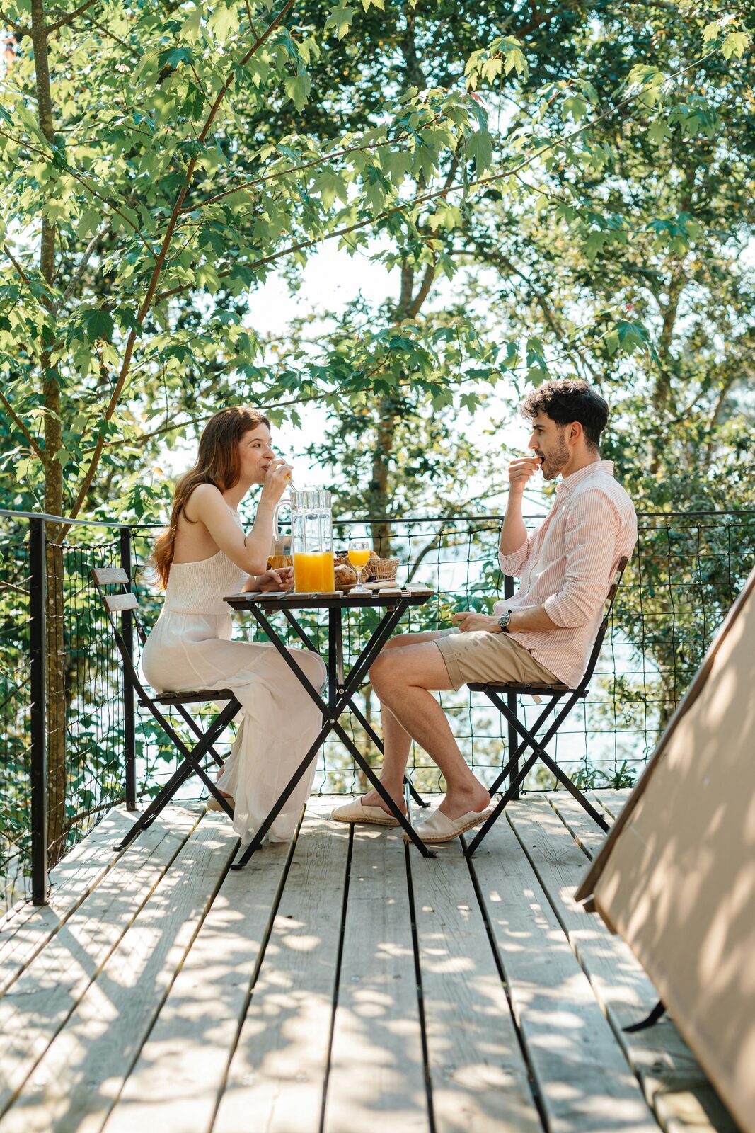 Connecticut couple enjoying an outdoor breakfast on a wooden deck among maple trees on a summer morning