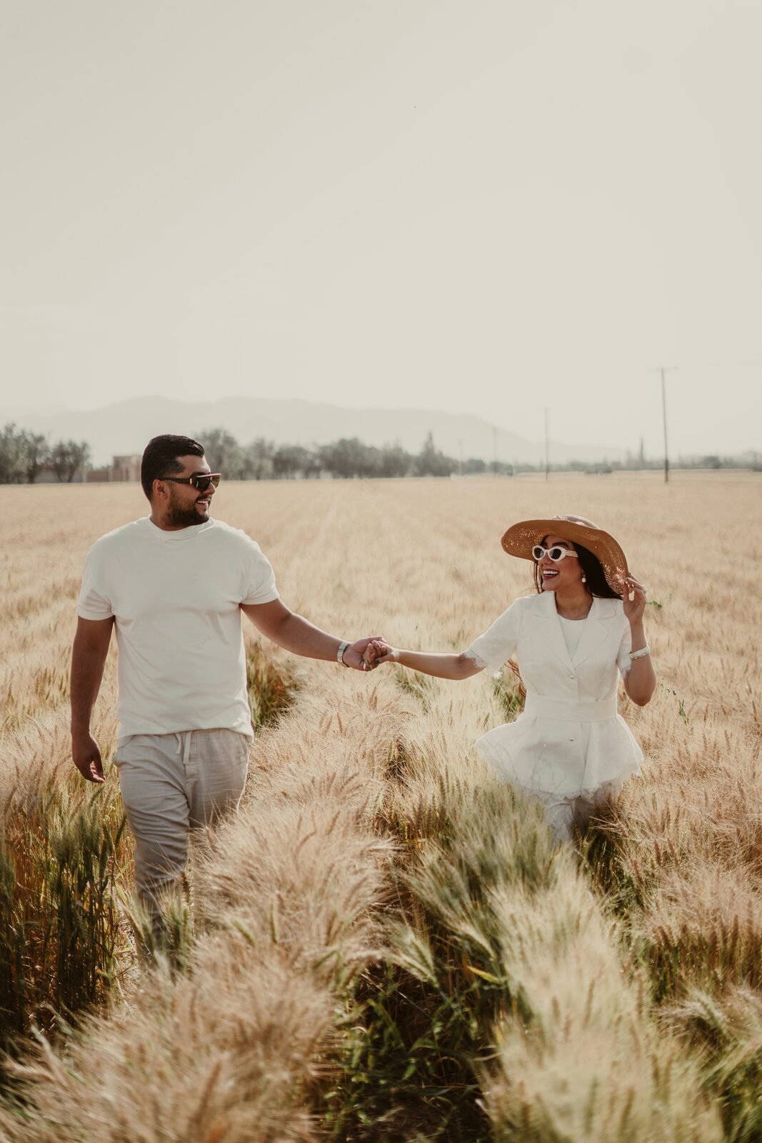 Maryland couple walking hand in hand through a golden wheat field
