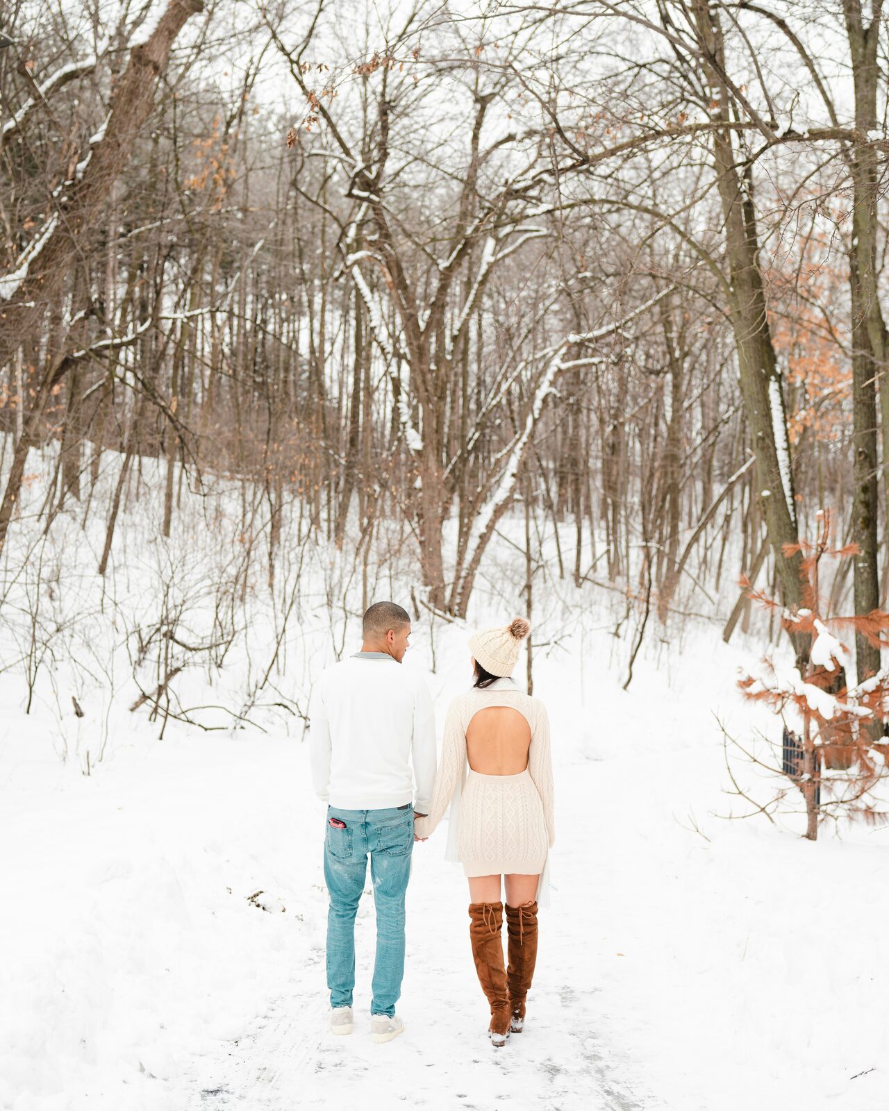 Engaged Wisconsin couple walking together through snowy woodland after finishing their prenup