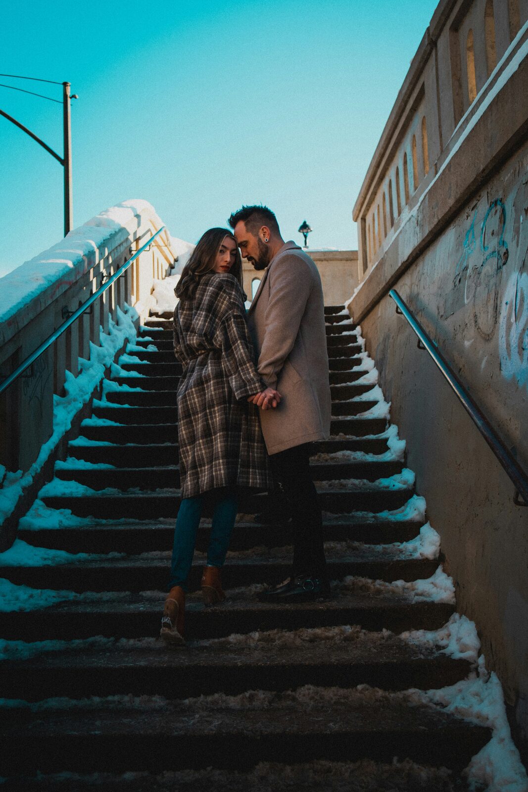 Engaged Wisconsin couple on a snowy city staircase after completing their attorney-backed prenup