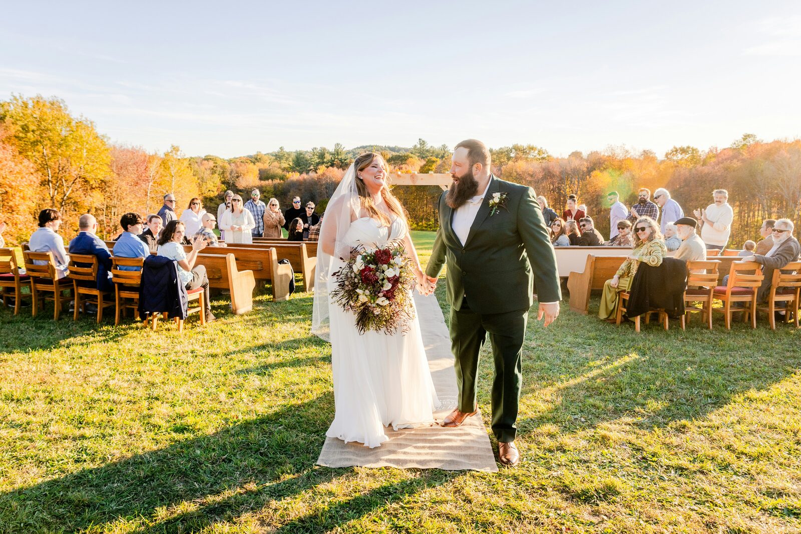 New England fall wedding recessional in Connecticut, the bride and groom walking past autumn foliage and outdoor ceremony pews