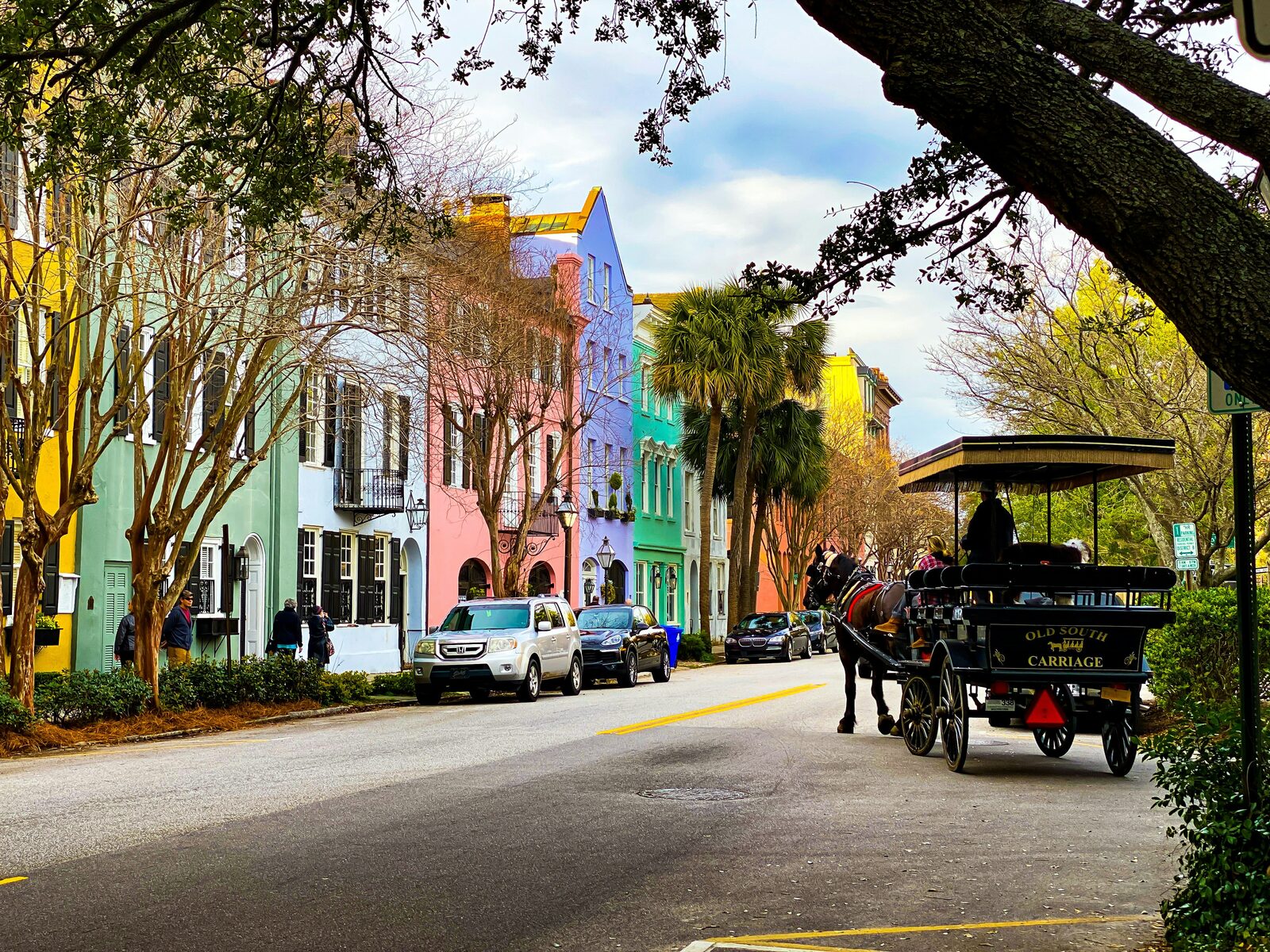 Rainbow Row in Charleston, South Carolina, with a horse-drawn carriage passing the pastel historic houses