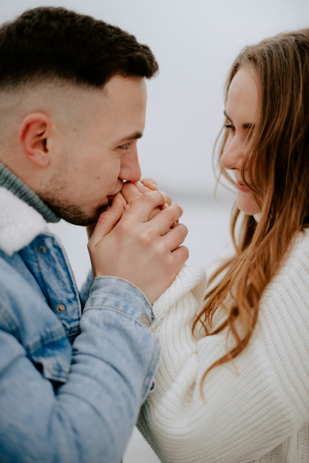Newly engaged Wisconsin couple close up as he warms her hands in the cold, before building their prenup