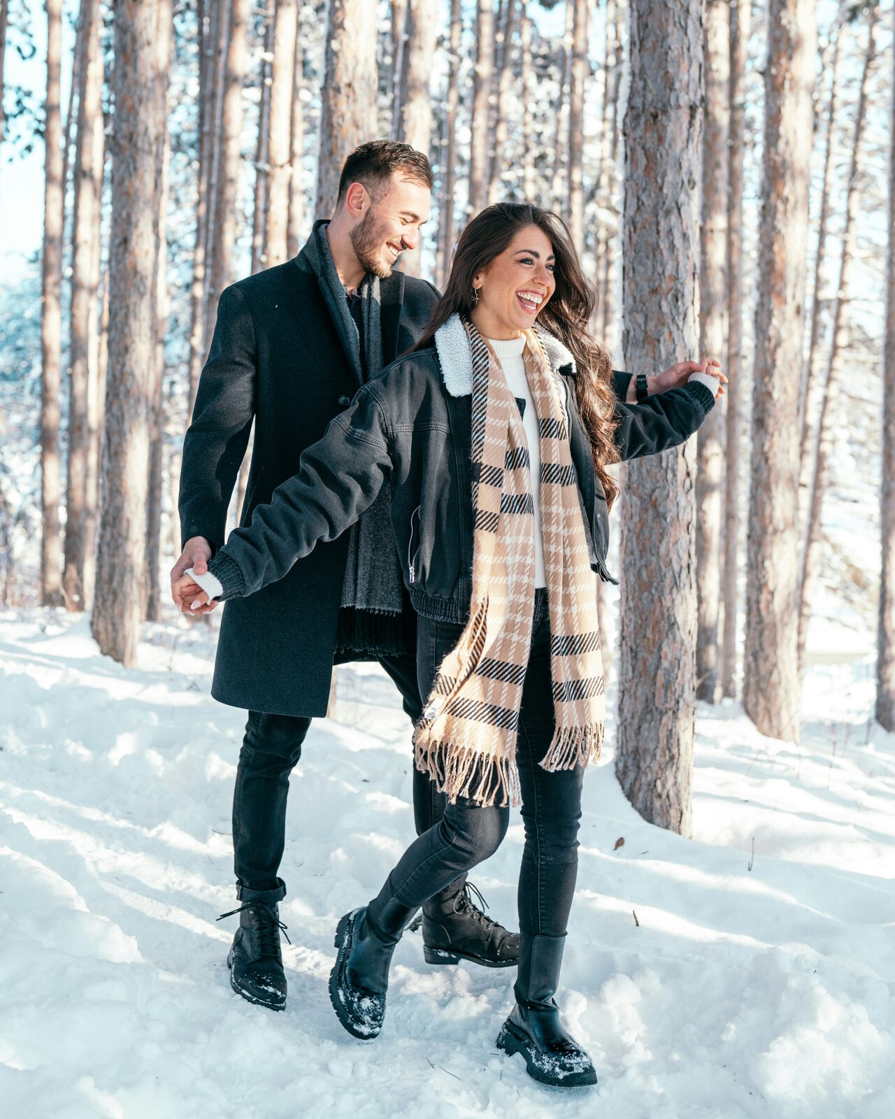 Engaged Wisconsin couple twirling together in a snowy birch forest