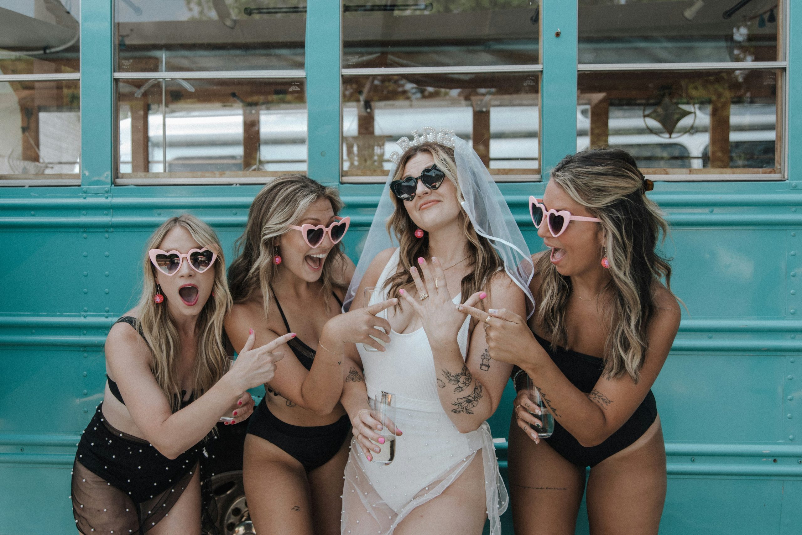 A bride posing happily with her friends during a bachelorette party, as the group celebrates together and smiles for the camera.
