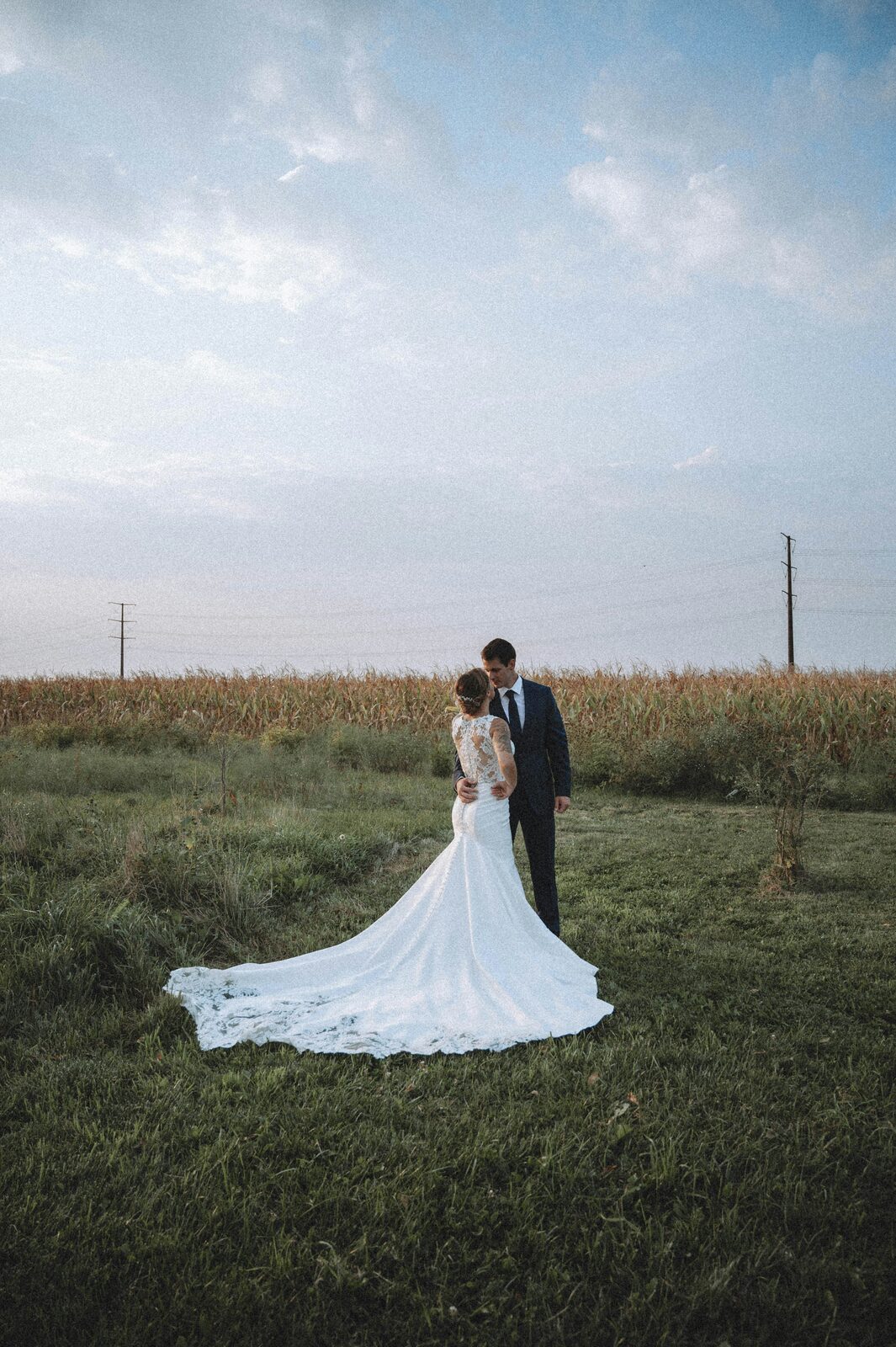 Missouri bride and groom in a lace mermaid gown and navy suit standing in a Midwest cornfield at golden hour on their wedding day, married with a HelloPrenup prenuptial agreement in place