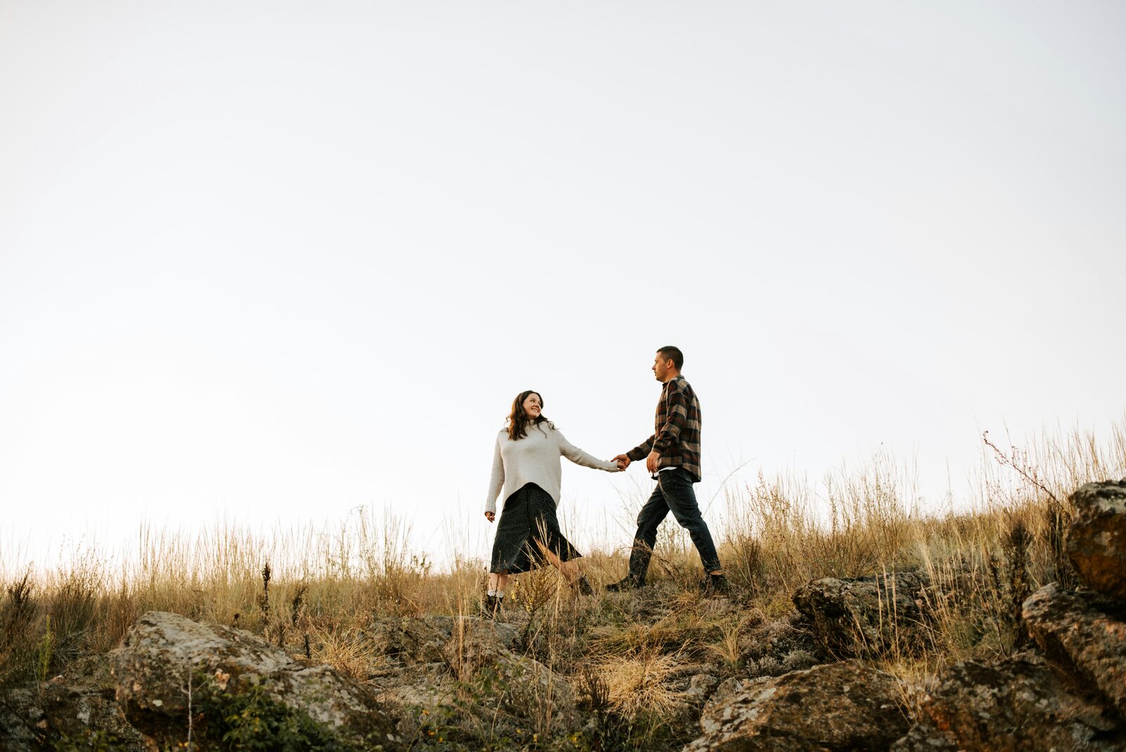 Missouri couple holding hands on a golden prairie hilltop at sunset in fall flannel, talking through marital property and alimony in their prenuptial agreement