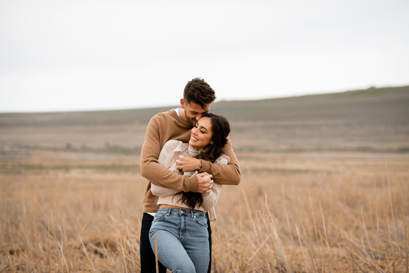 Missouri couple hugging in a golden prairie in a tan sweater and cream blouse after a stress-free prenup process
