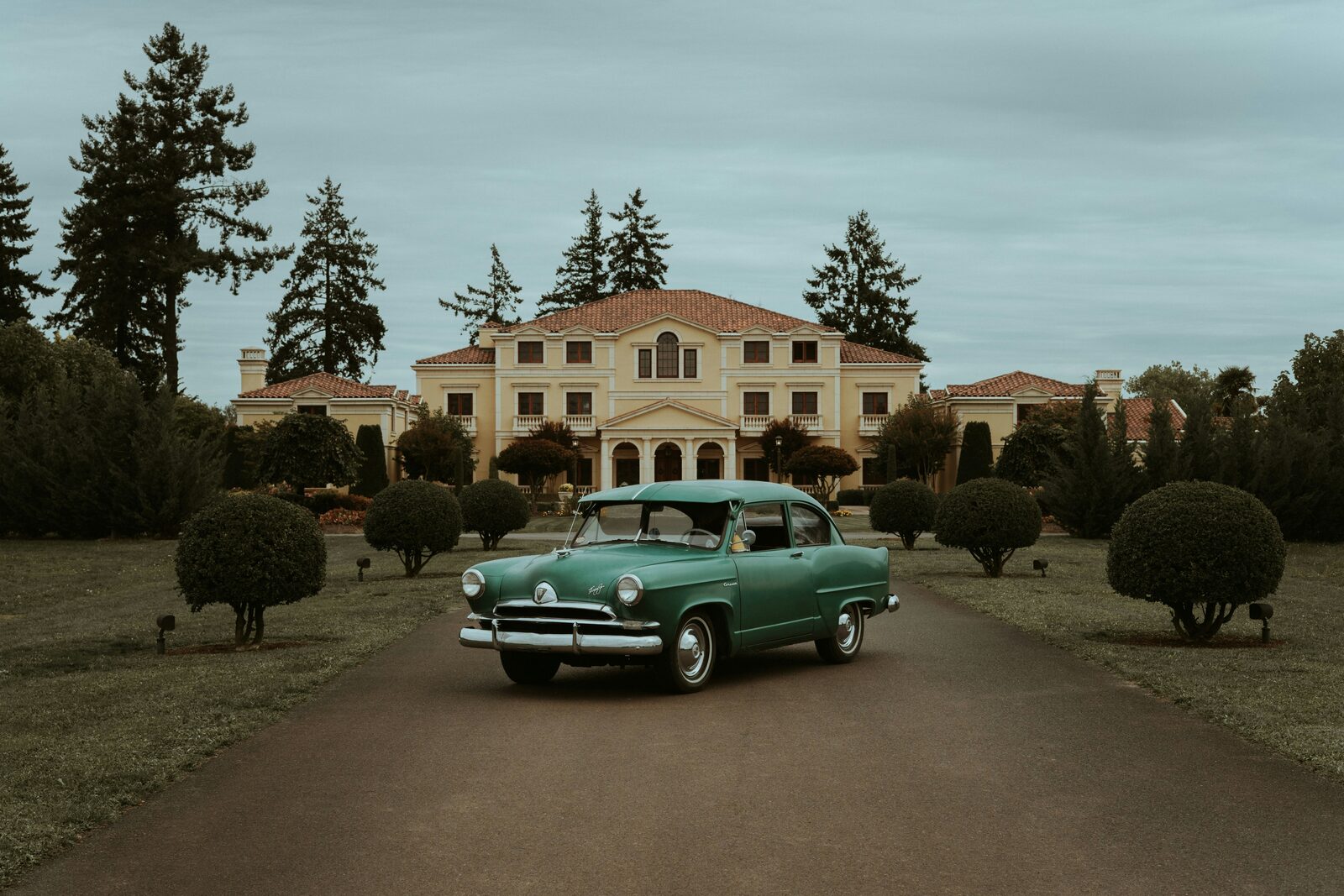 Vintage teal wedding getaway car parked outside a Mediterranean mansion
