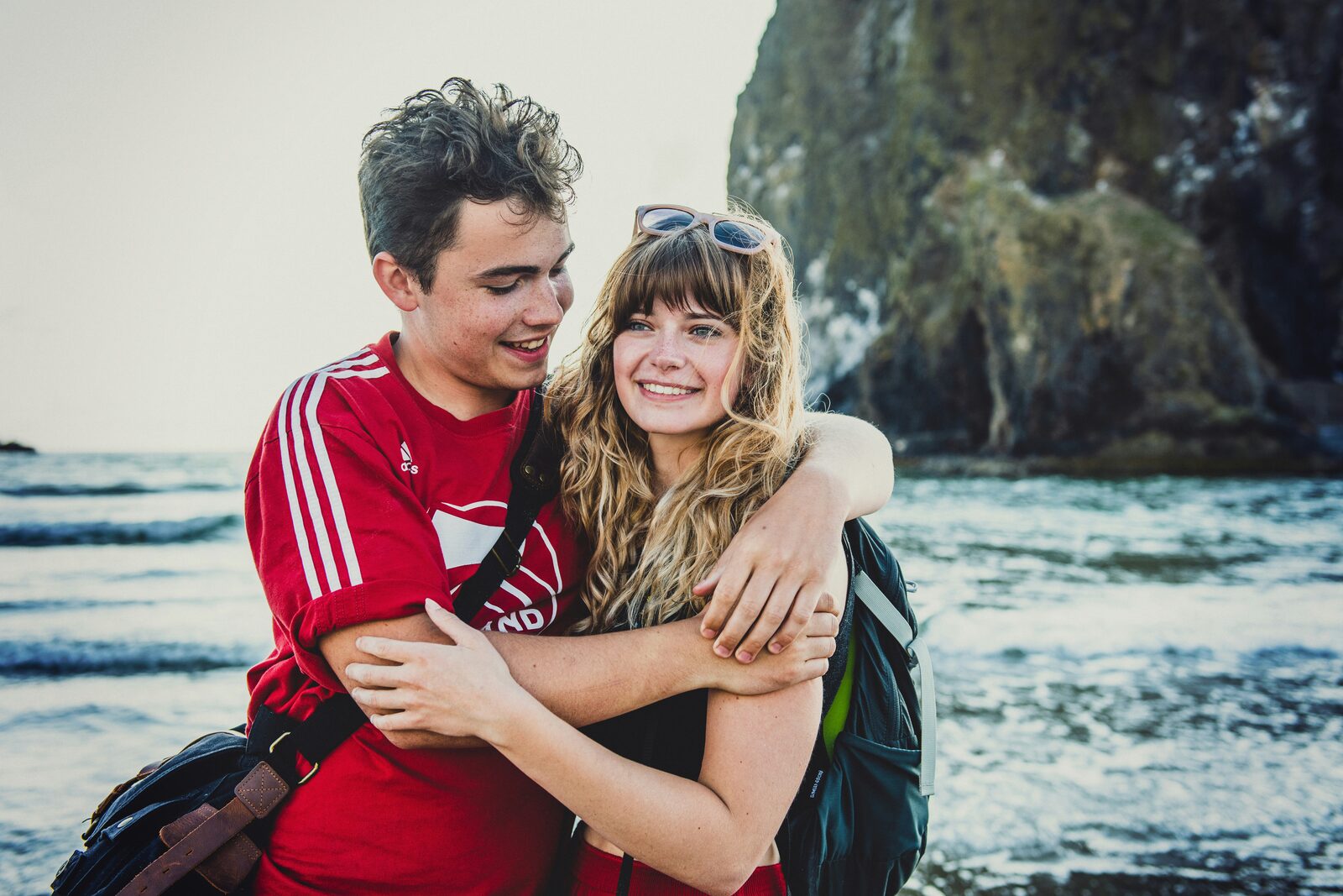 Engaged Oregon couple hugging on Cannon Beach beside Haystack Rock, protected with a HelloPrenup prenuptial agreement