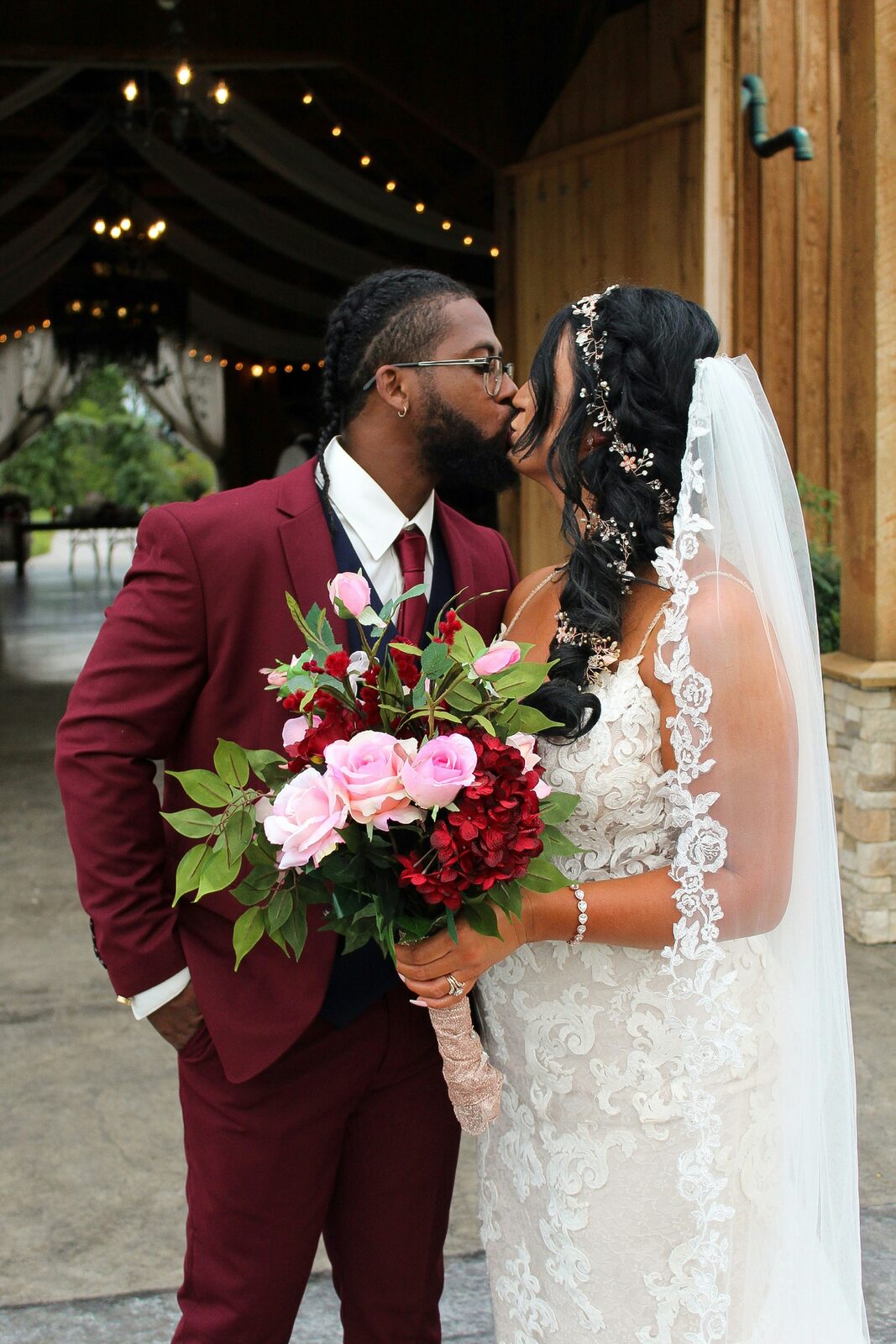 Kentucky bride and groom sharing a kiss in a rustic barn with pink roses, protected with a HelloPrenup prenuptial agreement