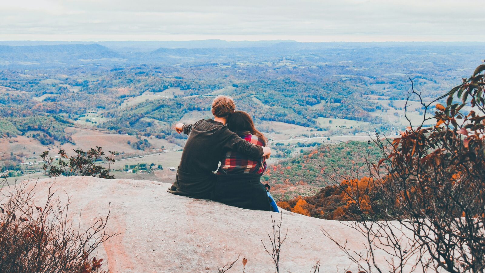 Couple embracing on a rocky mountain overlook in autumn, talking through the law behind their Utah prenup
