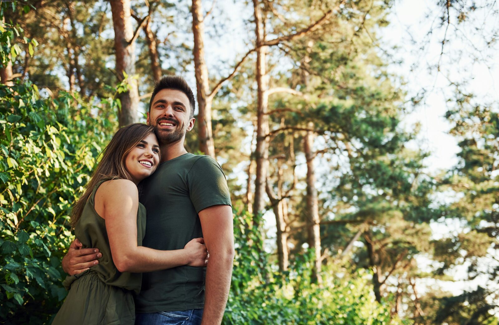 Indiana couple hugging in a sunlit pine forest, reflecting the property a prenup can protect