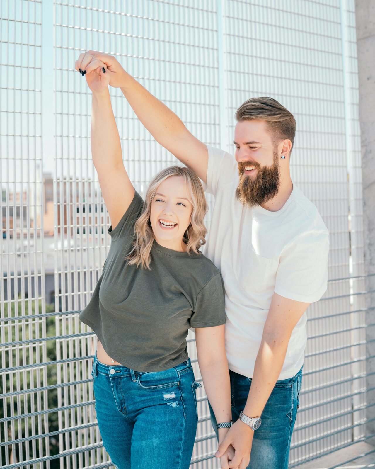 Engaged Louisiana couple twirling and laughing on an urban walkway