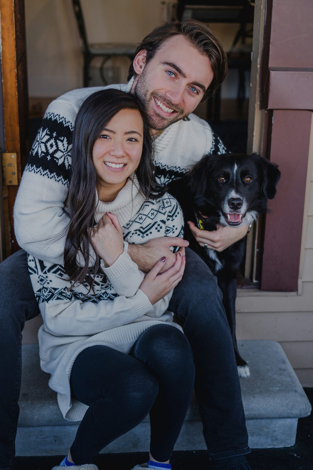 Indiana couple in matching Fair Isle sweaters on their front porch with their border collie as they prepare to build their prenup