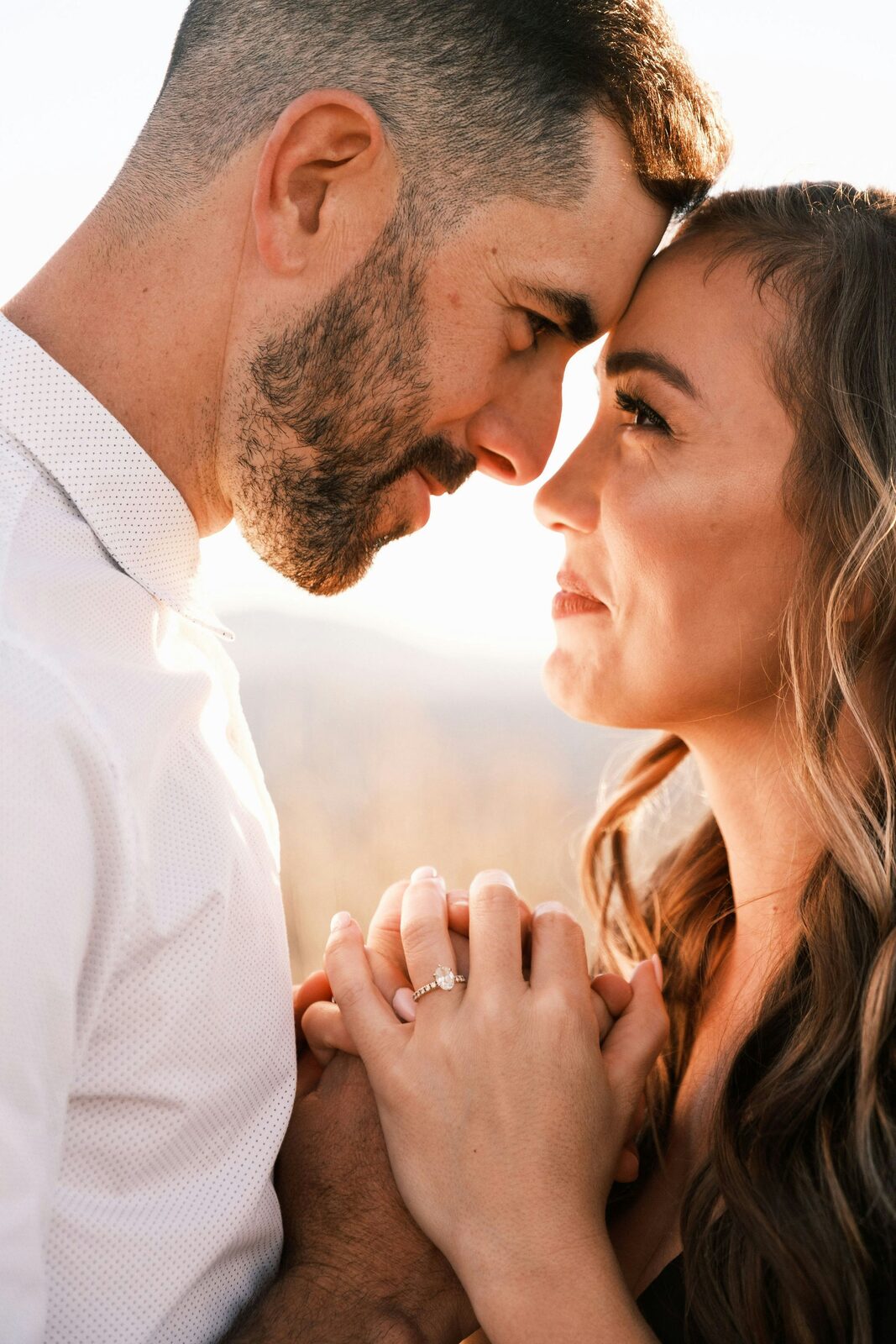Engaged Indiana couple touching noses at golden hour, her oval diamond engagement ring visible, protected with a HelloPrenup prenuptial agreement