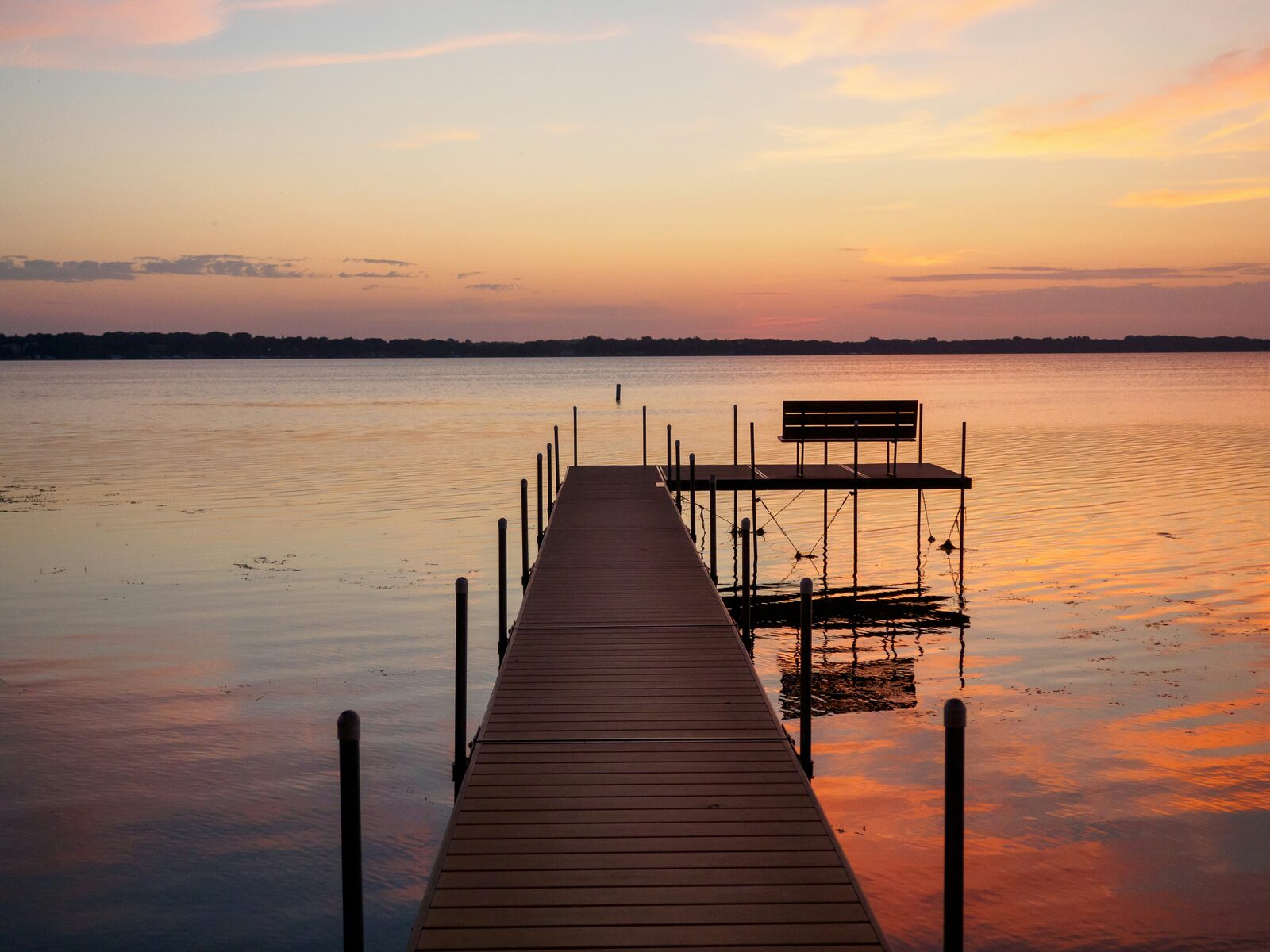 Dock and bench on Lake Okoboji in the Iowa Great Lakes at a pink sunset