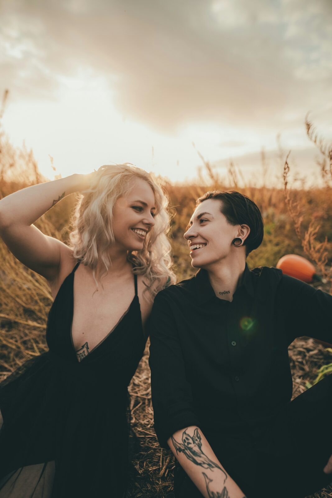 Two women sitting in a pumpkin patch at sunset, exploring their Iowa prenup options
