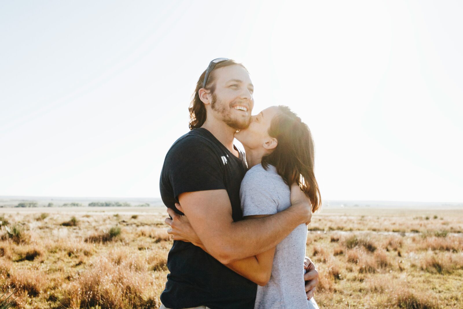 Engaged Indiana couple embracing on an open prairie in the sun
