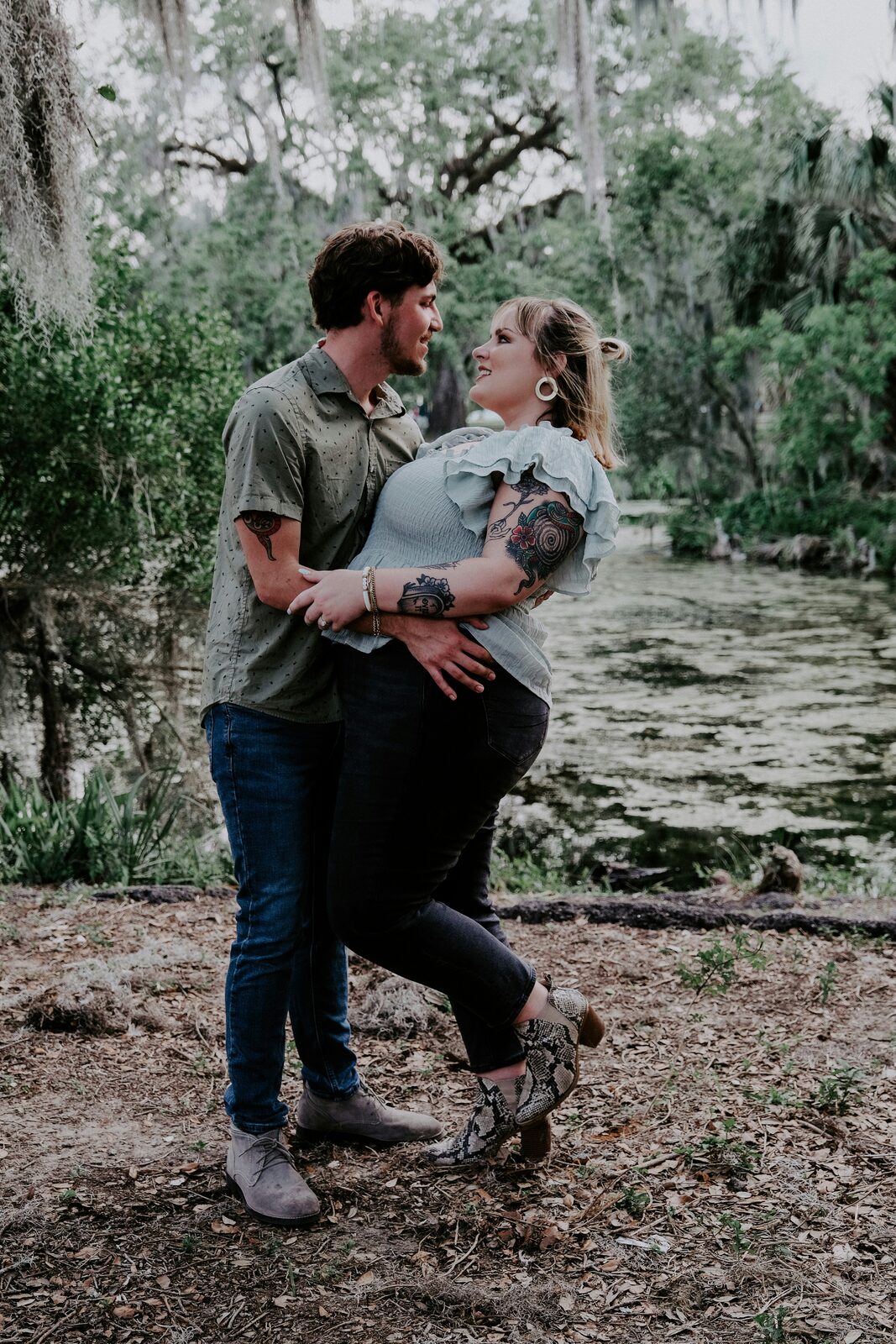 Engaged Louisiana couple embracing beside a bayou under Spanish moss, thinking through what they will own together