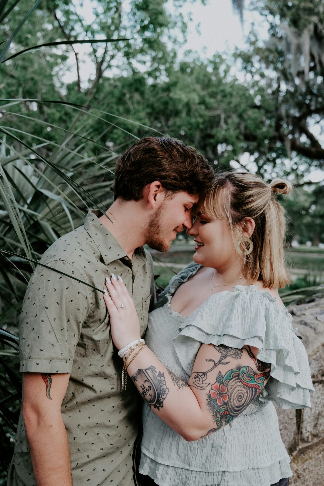 Engaged Louisiana couple touching foreheads under live oaks and Spanish moss after completing their attorney-backed prenup