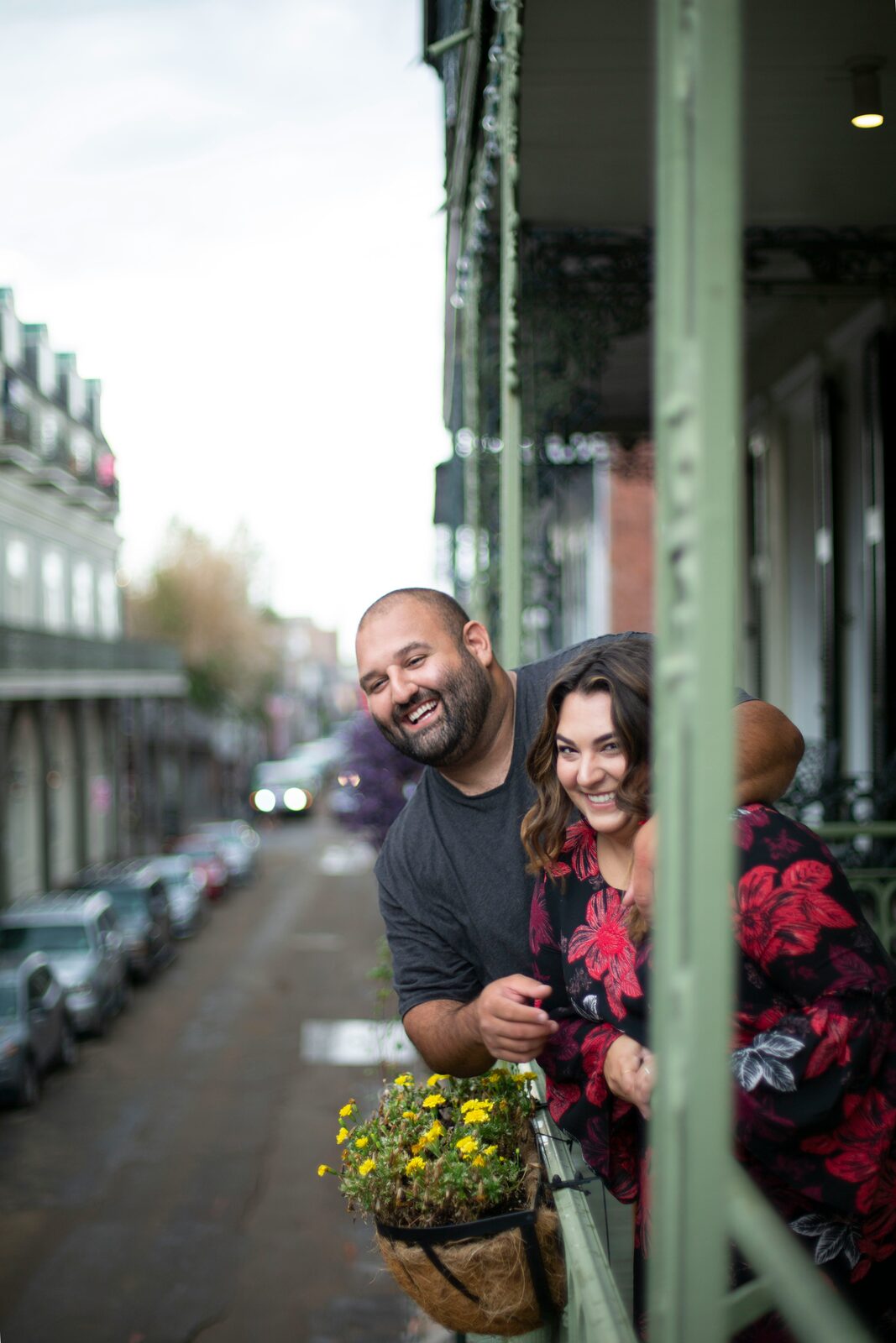 Engaged couple laughing on a French Quarter balcony in New Orleans, Louisiana, before building their prenup