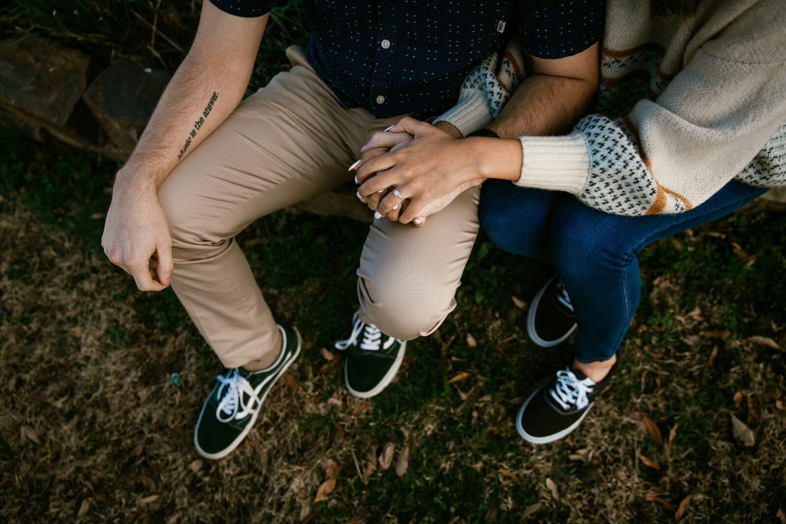 Engaged Kentucky couple sitting close in sneakers, showing off the engagement ring