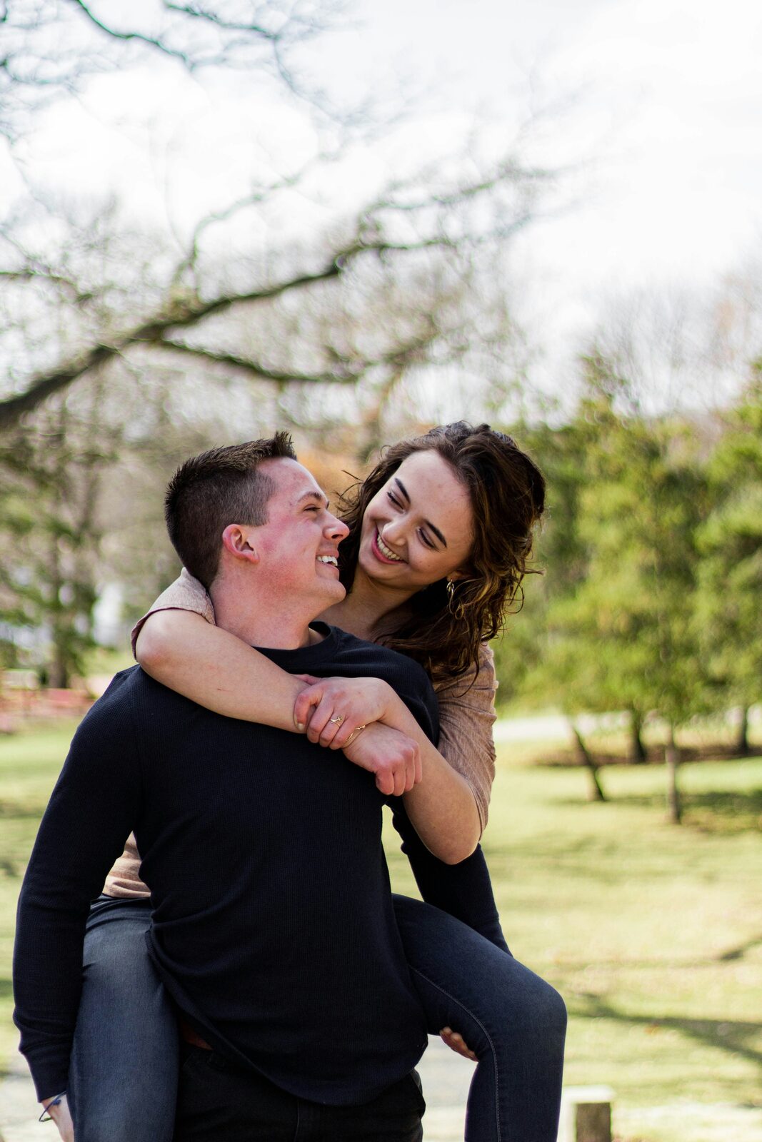 Indiana couple laughing during a piggyback ride in a spring park after a stress-free prenup process