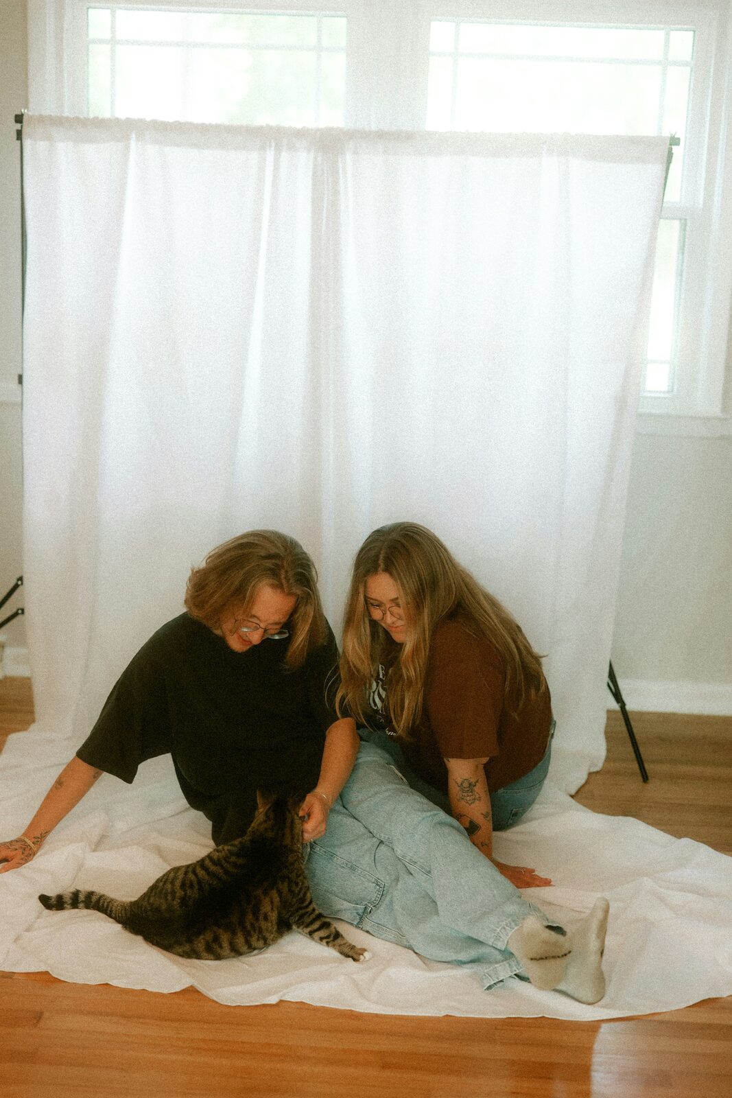 Two women sitting with their tabby cat in a sunlit studio, reflecting the range of assets a prenup can protect
