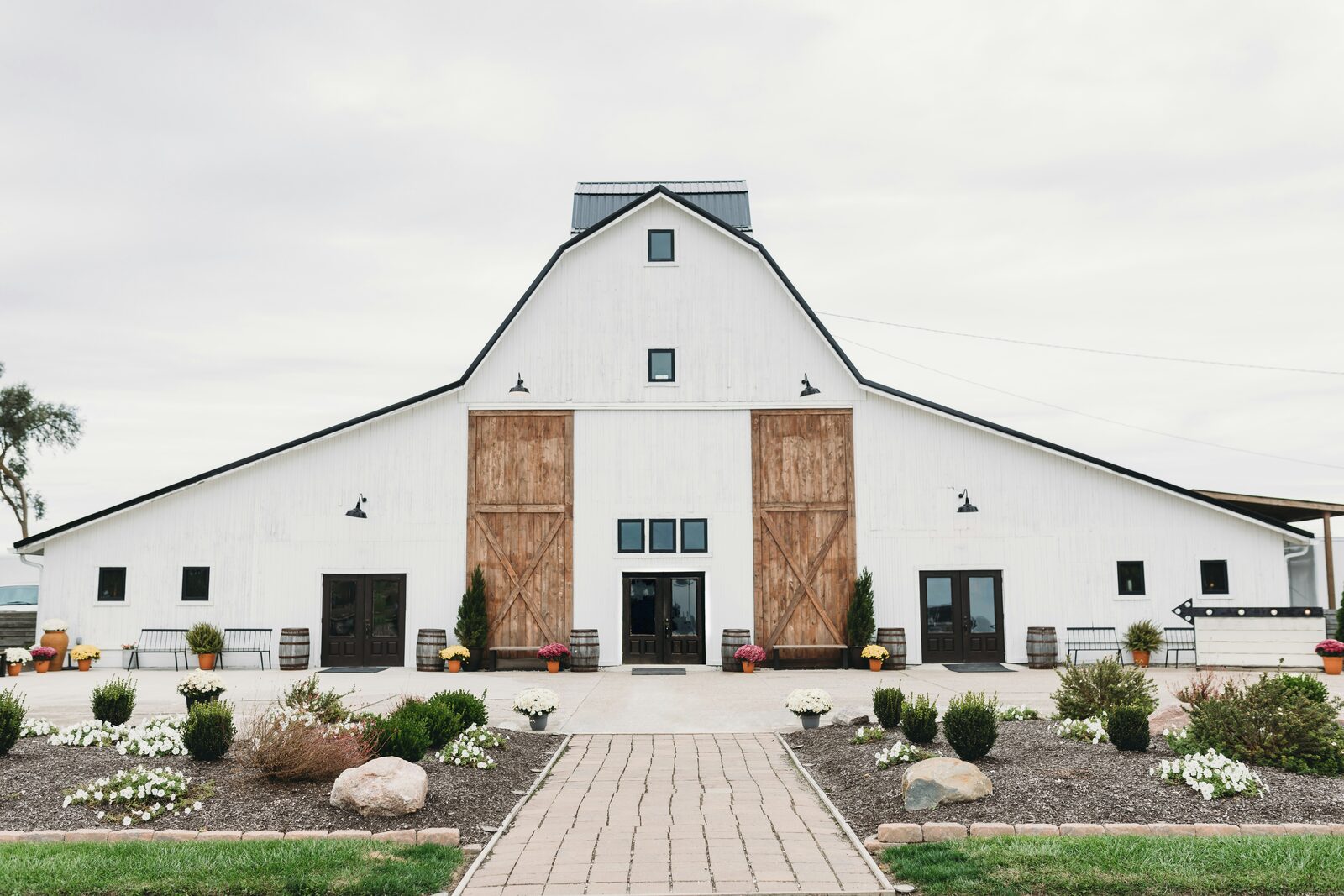 White rustic barn wedding venue with sliding barn doors and a landscaped path